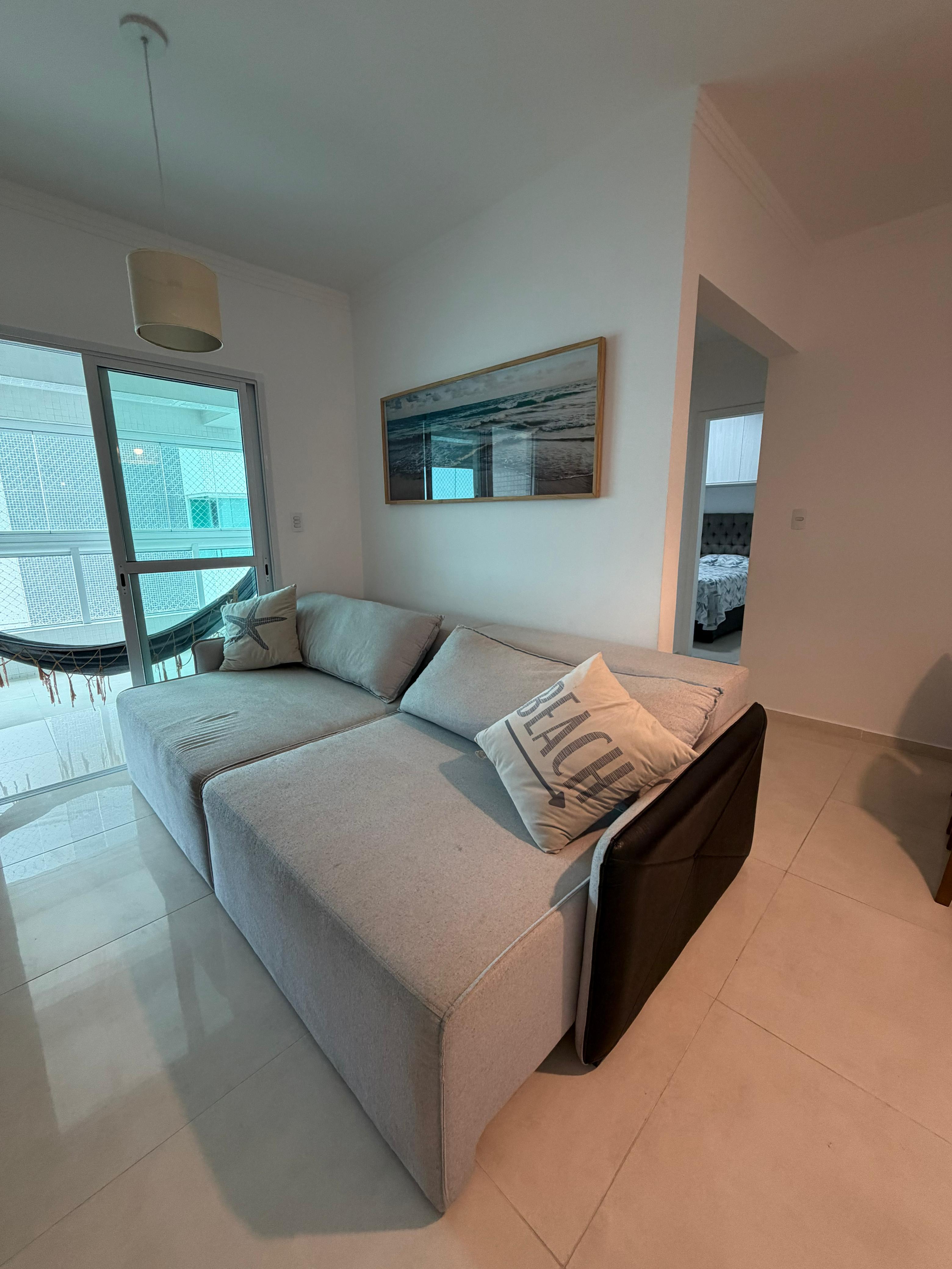 Sala de estar com sofá e acesso à sacada